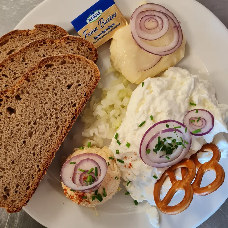 Hausgemachter Obazda und Kochkäse mit Bauernbrot, roten Zwiebeln und Brezeln